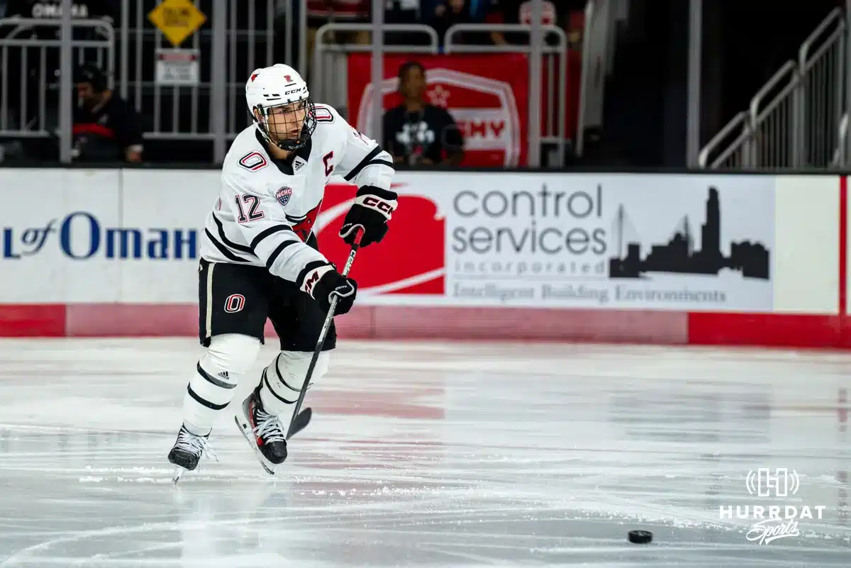 Omaha Maverick Nolan Krenzen (12) passes the puck against the Wisconsin Badgers in a college hockey match Saturday, October 5, 2024 in Omaha, Nebraska. Photo by Kyle Byers.