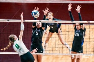 Kearney Catholic's Hazel Haarberg (8) spikes the ball against Minden's's Kinsie Land (9) and Makenna Starkey (25) during the semi-finals of the 2024 NSAA Volleyball Championships Friday, November 8, 2024, in Lincoln, Nebraska. Photo by Mike Sautter.