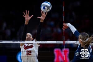 Nebraska Cornhuskers outside hitter Taylor Landfair (12) jumps to try block Penn State Nittany Lions middle blocker Maggie Mendelson (44) during the semi-final round in the NCAA championship Thursday, December 19, 2024, in Louisville, Kentucky. Photo by John S. Peterson.