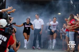 Nebraska Cornhusker Lexi Rodriguez (8), John Cook, and Merritt Beason (13) lead the Huskers out to the court to take on Omaha Mavericks during Nebraska Volleyball Day match in Lincoln, Nebraska, Wednesday, August 30, 2023. Photo by John Peterson.