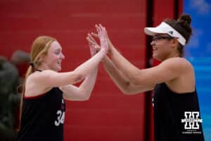 Nebraska Cornhuskers Rebekah Allick (5) and Olivia Mauch (34) high five each other after a point during a college beach volleyball match Tuesday, March 4, 2025 in Lincoln, Nebraska. Photo by John S. Peterson.