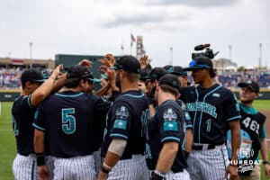 Coastal Carolina Chanticleers huddle up before taking on the Louisville Cardinals during the College World Series on Wednesday, June 18, 2025 in Omaha, Nebraska. Photo by John S. Peterson.