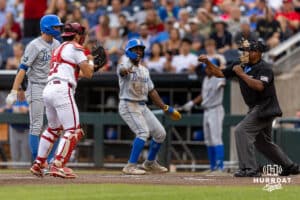The umpire signals out after Arkansas Razorback catcher Ryder Helfrick (27) tags UCLA Bruin outfielder Dean West (36) trying to steal home in the first inning during the College World Series on Tuesday, June 17, 2025 in Omaha, Nebraska. Photo by John S. Peterson.