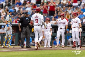 Arkansas Razorback infielder Wehiwa Aloy (9) runs home with Charles Davalan, Logan Maxwell, and the batboy waiting after hitting a two-run home run against the UCLA Bruins in the first inning during the College World Series on Tuesday, June 17, 2025 in Omaha, Nebraska. Photo by John S. Peterson.