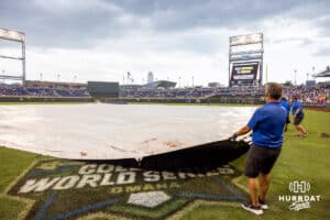 The grounds crew pull the trap over the infield preparing for the rain soon to come during the College World Series game between the LSU Tigers and the UCLA Bruins on Monday, June 16, 2025 in Omaha, Nebraska. Photo by John S. Peterson.