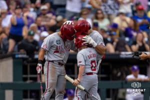 Arkansas Razorback catcher Ryder Helfrick (27), right, celebrates his home run with Cam Kozeal and the bat boy against the LSU Tigers in the fourth inning during the College World Series on Wednesday, June 18, 2025 in Omaha, Nebraska. Photo by John S. Peterson.
