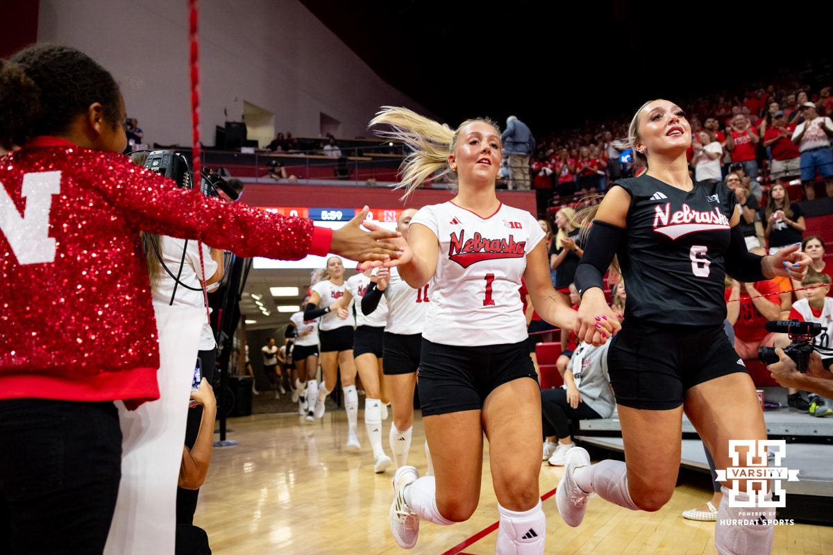 Nebraska Cornhusker Keri Leimbach (1) runs out to the court with Laney Choboy (6) and giving five to a young fan before the start of the Nebraska alumni match on Saturday, Aug. 16, 2025 in Lincoln, Nebraska. Photo by John S. Peterson.