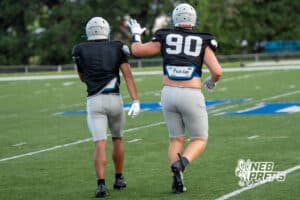 Nate Maraable helps a teammate during Millard North football practice on Saturday, August 16th, 2025 in Omaha, Nebraska. Photo by Brandon Tiedemann.